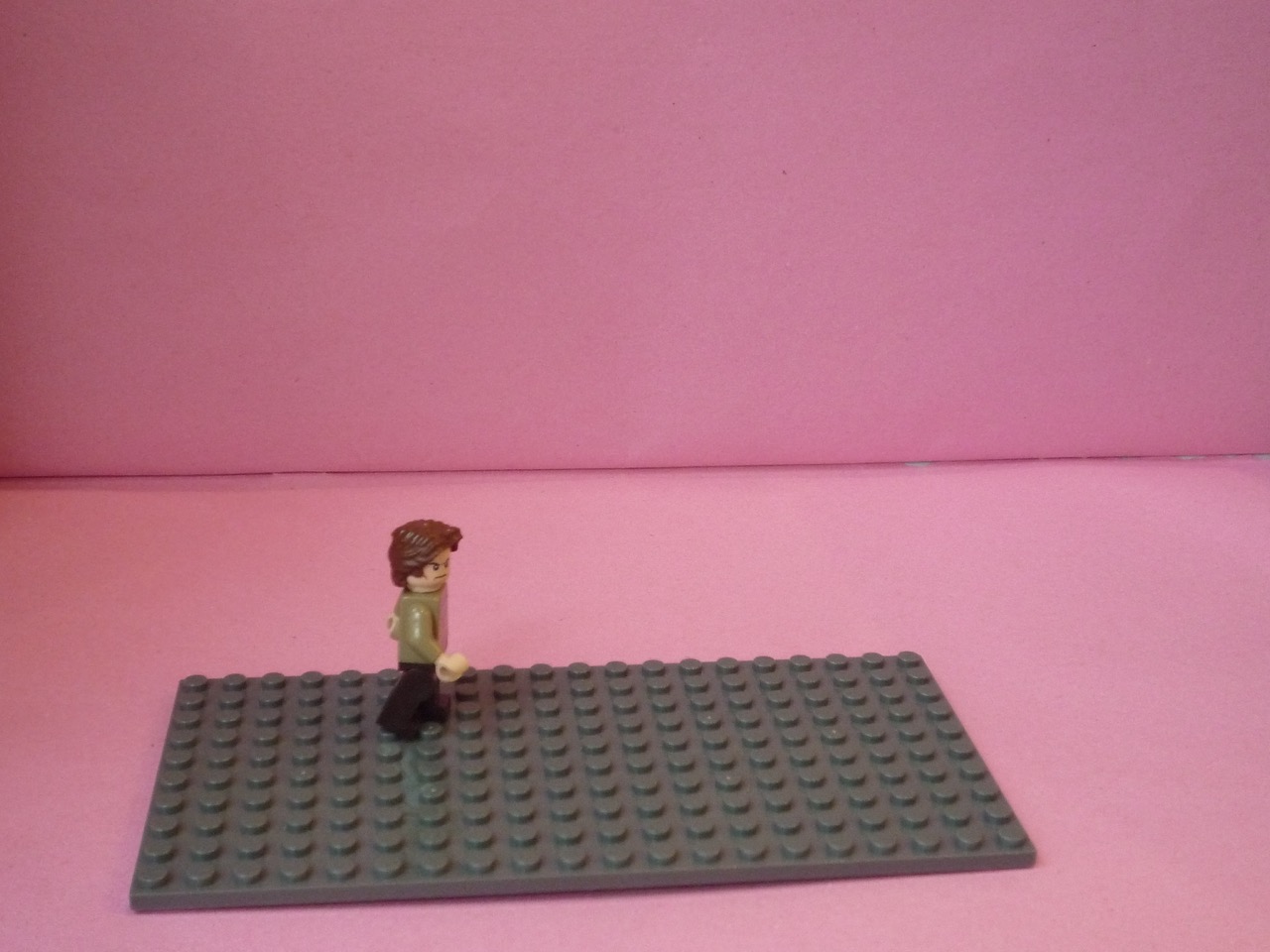 A minifigure on a baseplate against coloured card